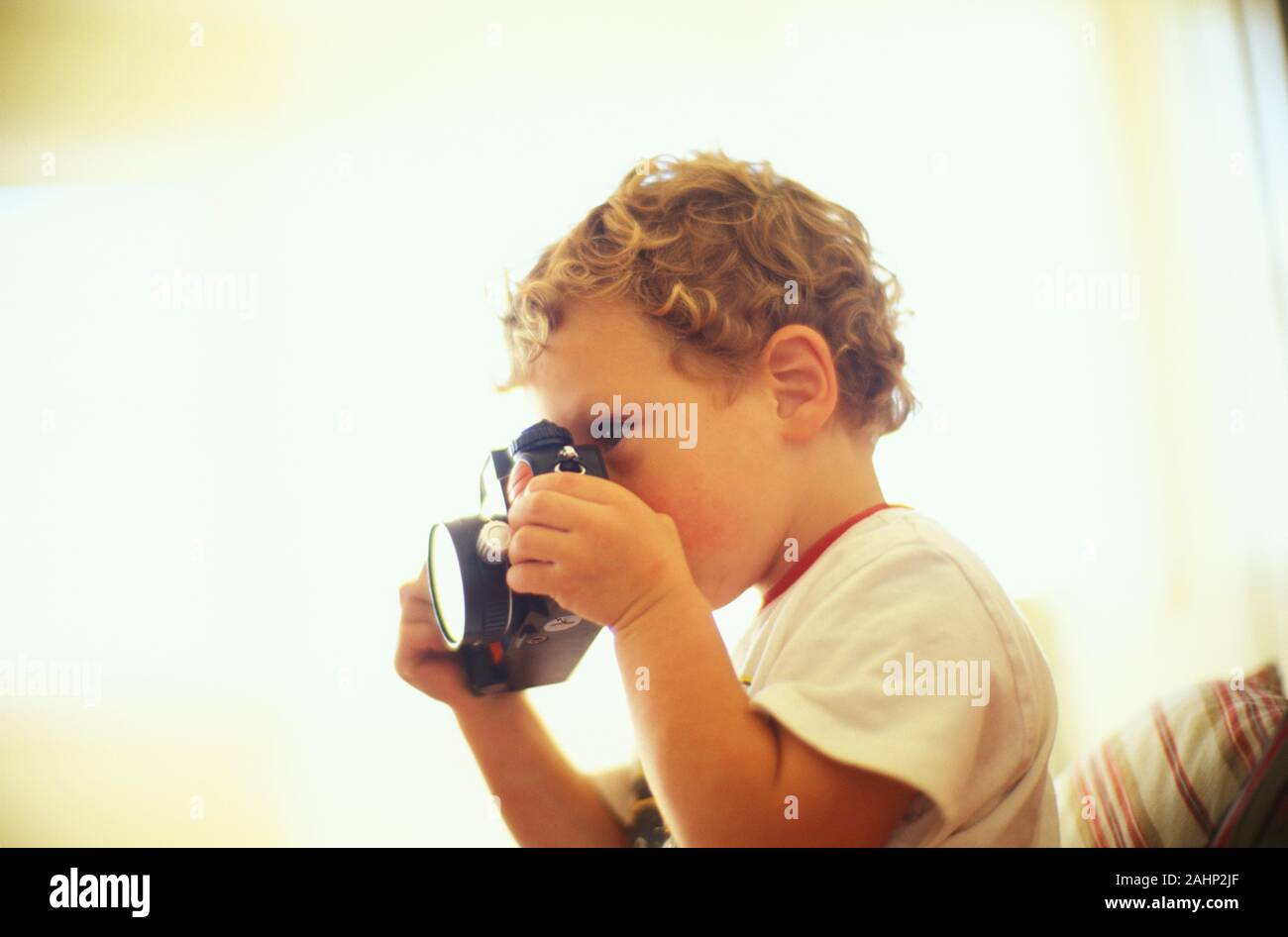 Side view of a little boy looking through the lens of a camera Stock ...
