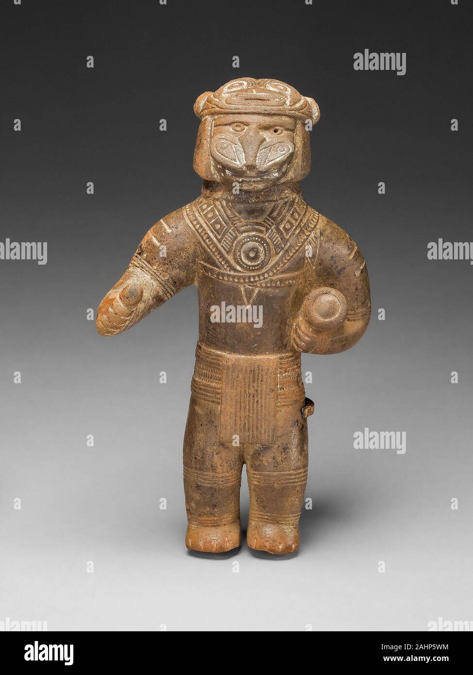 Tairona. Masked Figurine Holding a Drum, Possibly a Ocarina (Whistle). 1200–1400. Colombia. Ceramic and pigment To this day in Tairona communities, masked individuals dance, personifying the deified forces and phenomena of nature. This act associates the annual round of social and economic activities with the natural world’s cycle of death, fertility, and renewal. Stock Photo