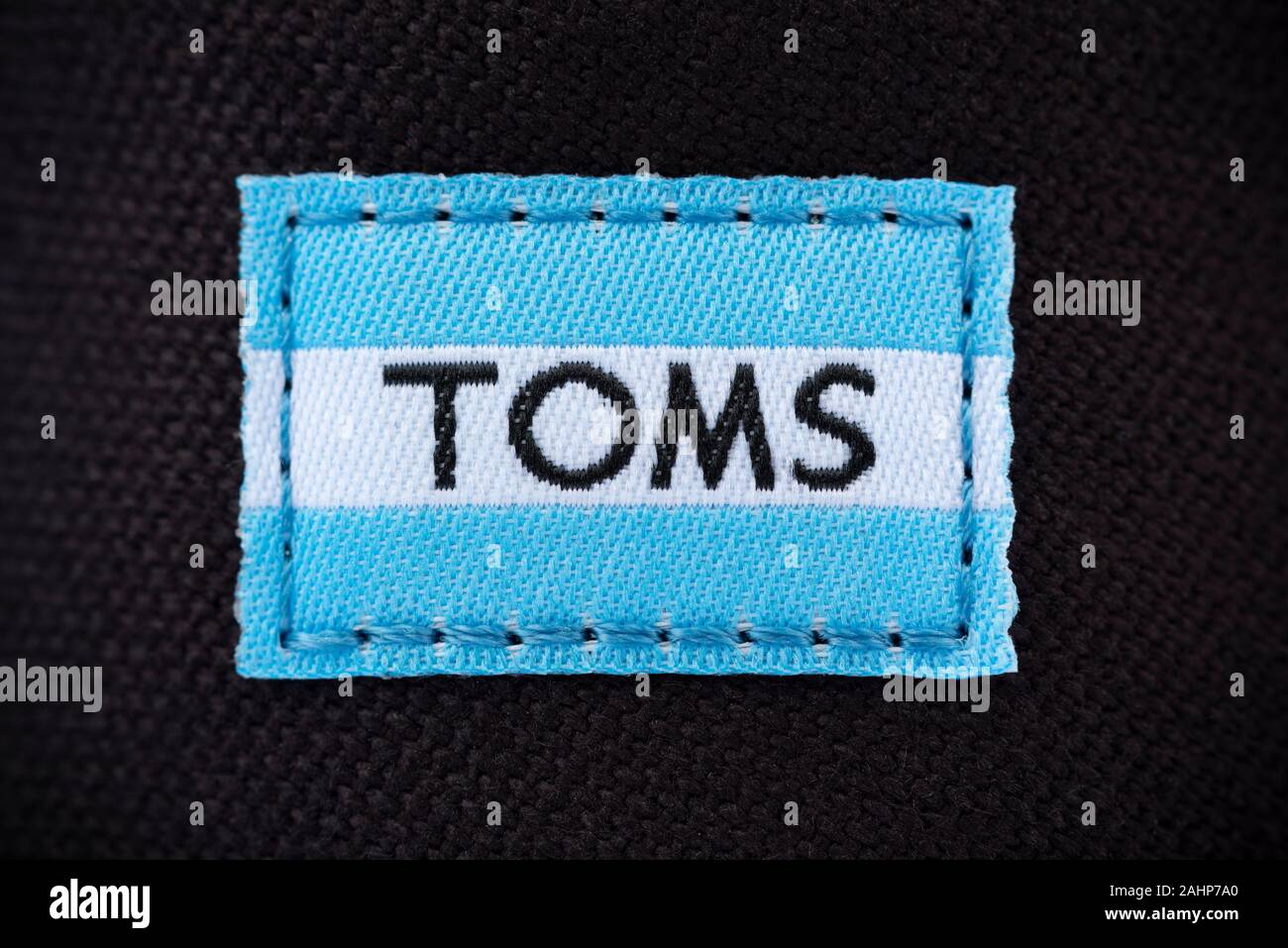 The logo of the brand Toms Shoes as seen as a label stitched on to one