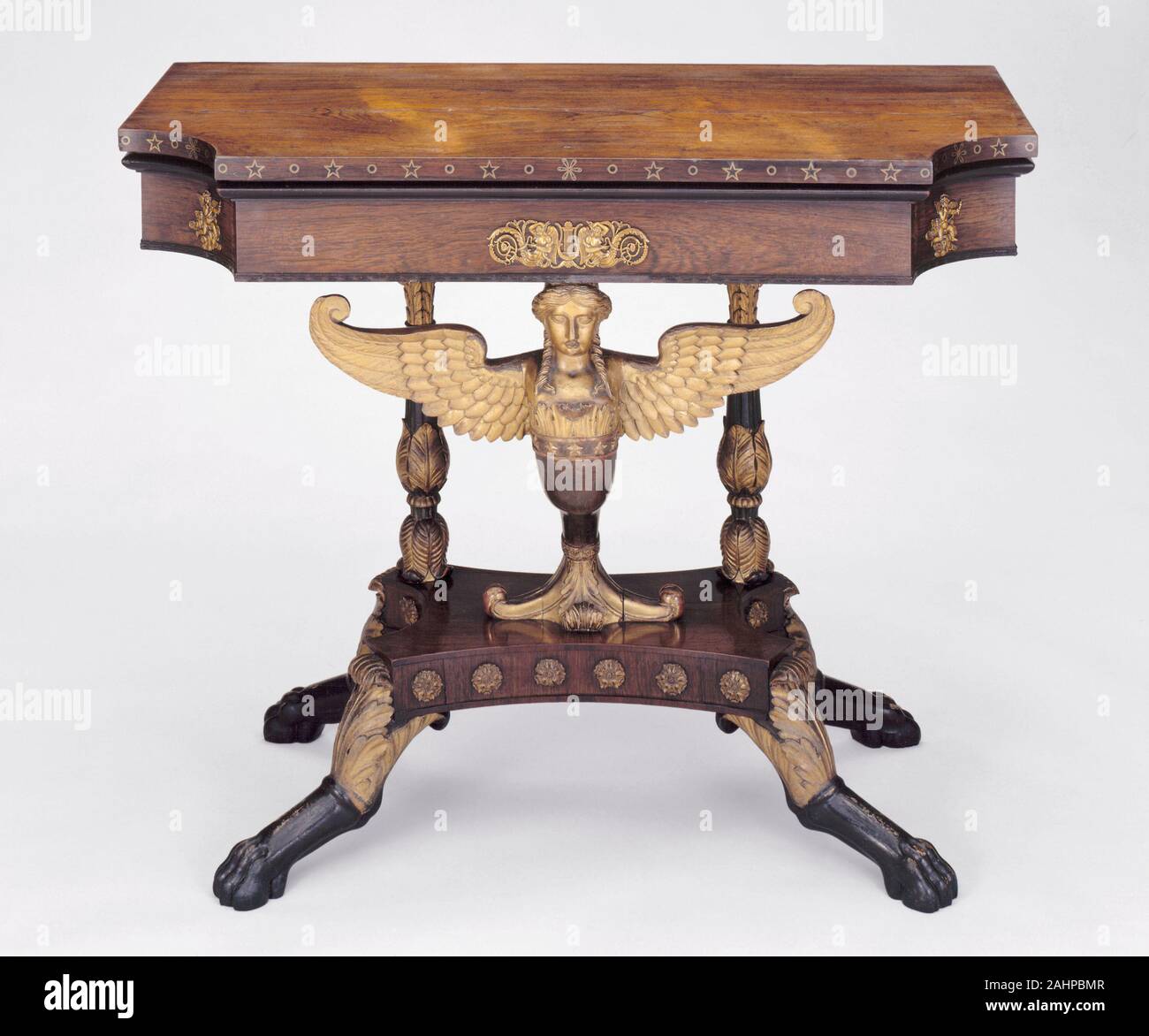 Charles-Honoré Lannuier. Card Table. 1815. New York. Mahogany with rosewood veneer, giltwood, brass and ebony inlay, ormolu Trained as a cabinet-maker in Paris, Charles-Honoré Lannuier arrived in New York in 1803 at the age of twenty-four. His older brother was already well established as the owner of a successful confectionary shop on Broadway and from there the young furniture maker first advertised his services to all potential clients who desired furniture in the “latest French fashion.” Early-nineteenth-century America was much enamored with French taste, and Lannuier successfully catered Stock Photo
