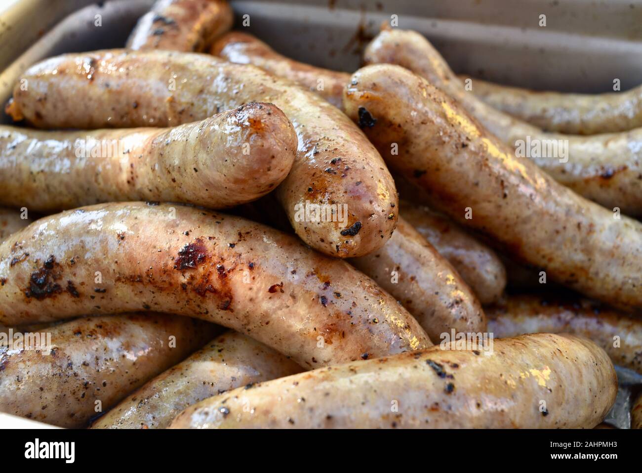 Grilled bratwurst sausages piled up in a serving tray for sale at
