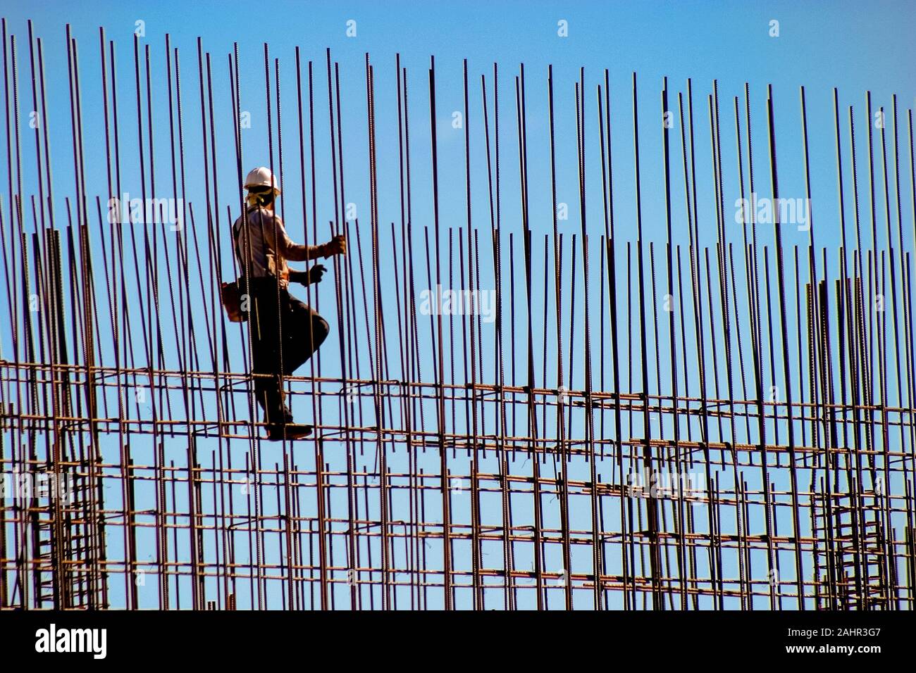 Construction worker in hard hat standing on rows of thin rebar Stock Photo