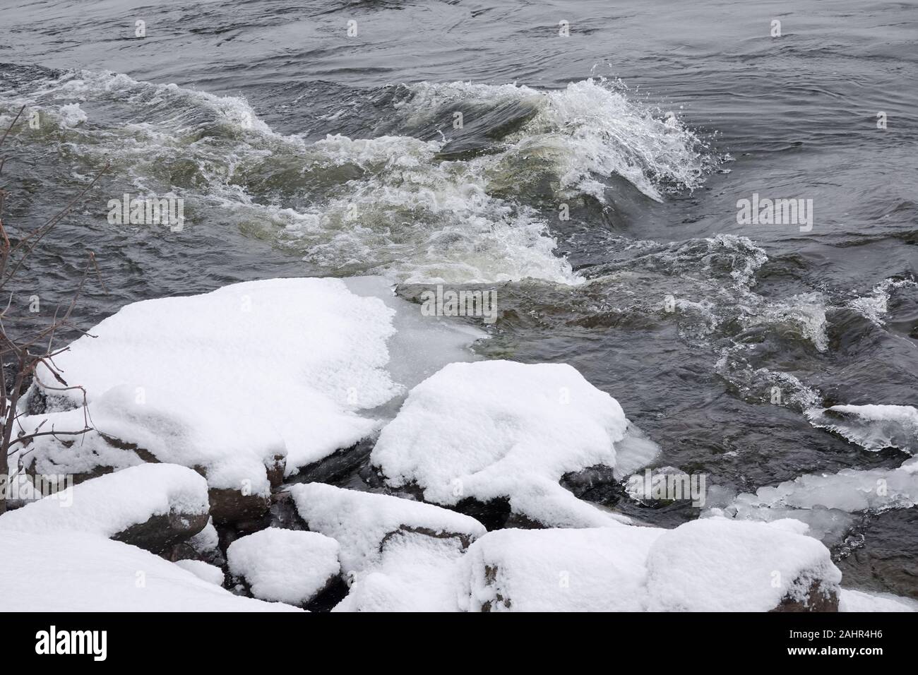 wavy water near snow accumulation on the rocks at the shore of saint lawrence in montreal during winter 2020 Stock Photo