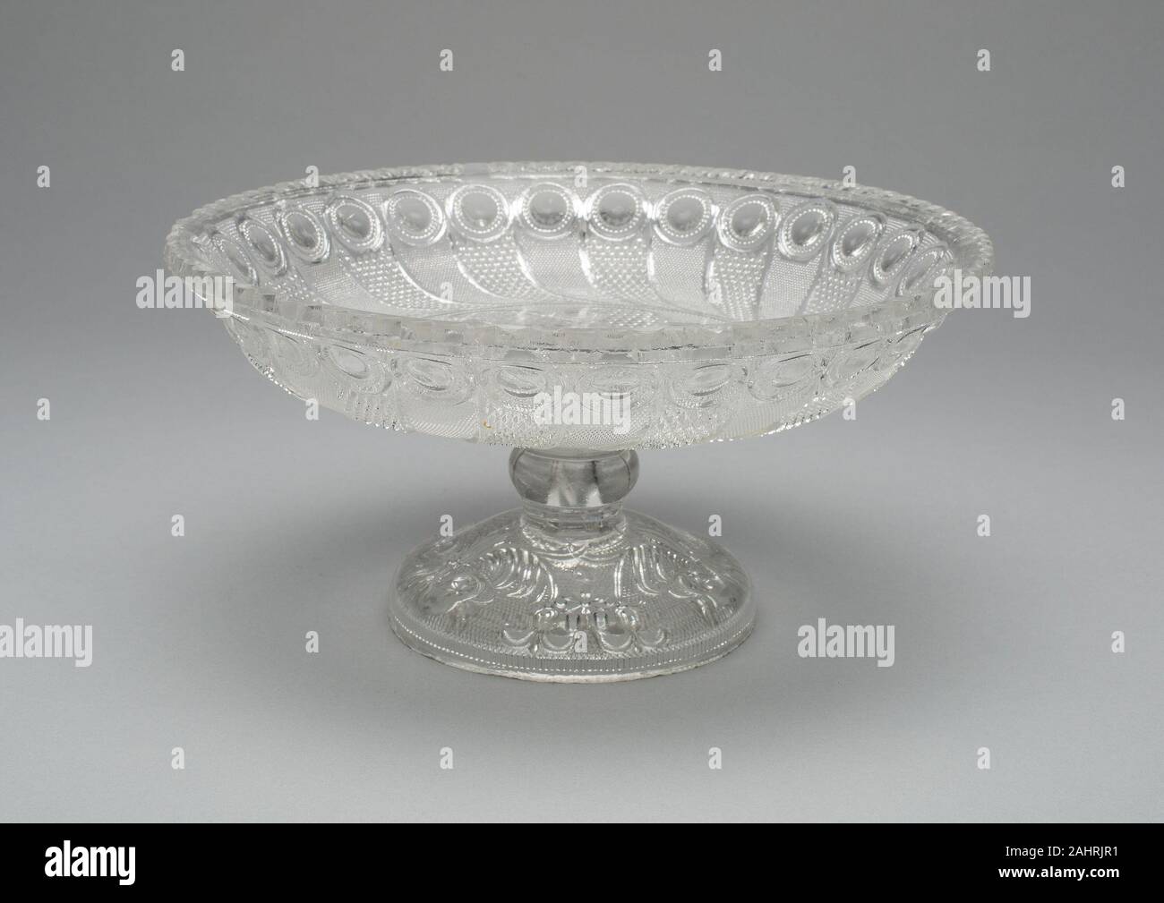 Boston and Sandwich Glass Company (Manufacturer). Compote. 1835–1850. Boston. Pressed glass The patterns on this rare compote—a peacock-feather border with a scrolled-eye center—were two of the most important and popular early-19th-century American patterns produced. For Americans, such pressed designs were less expensive and more accessible alternatives to the cut glass produced in Great Britain and Continental Europe. Stock Photo