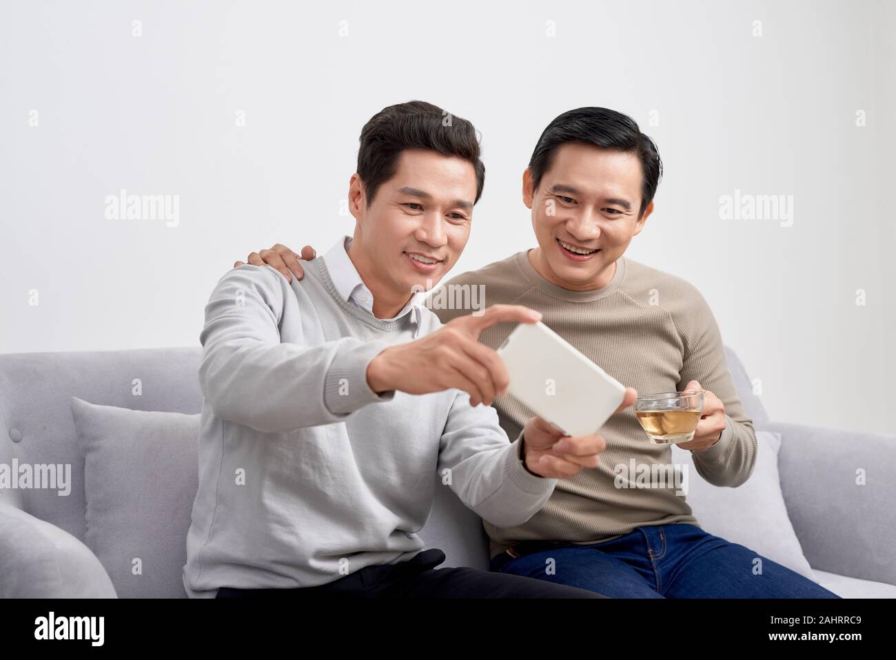 Cheerful young men dressed in casual wear smiling at camera while making selfie photo on front camera Stock Photo