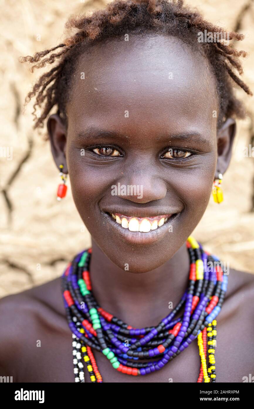 Portrait of a girl from Dassanech tribe in front of a cracked walls of a traditional house, Omo valley, Ethiopia Stock Photo