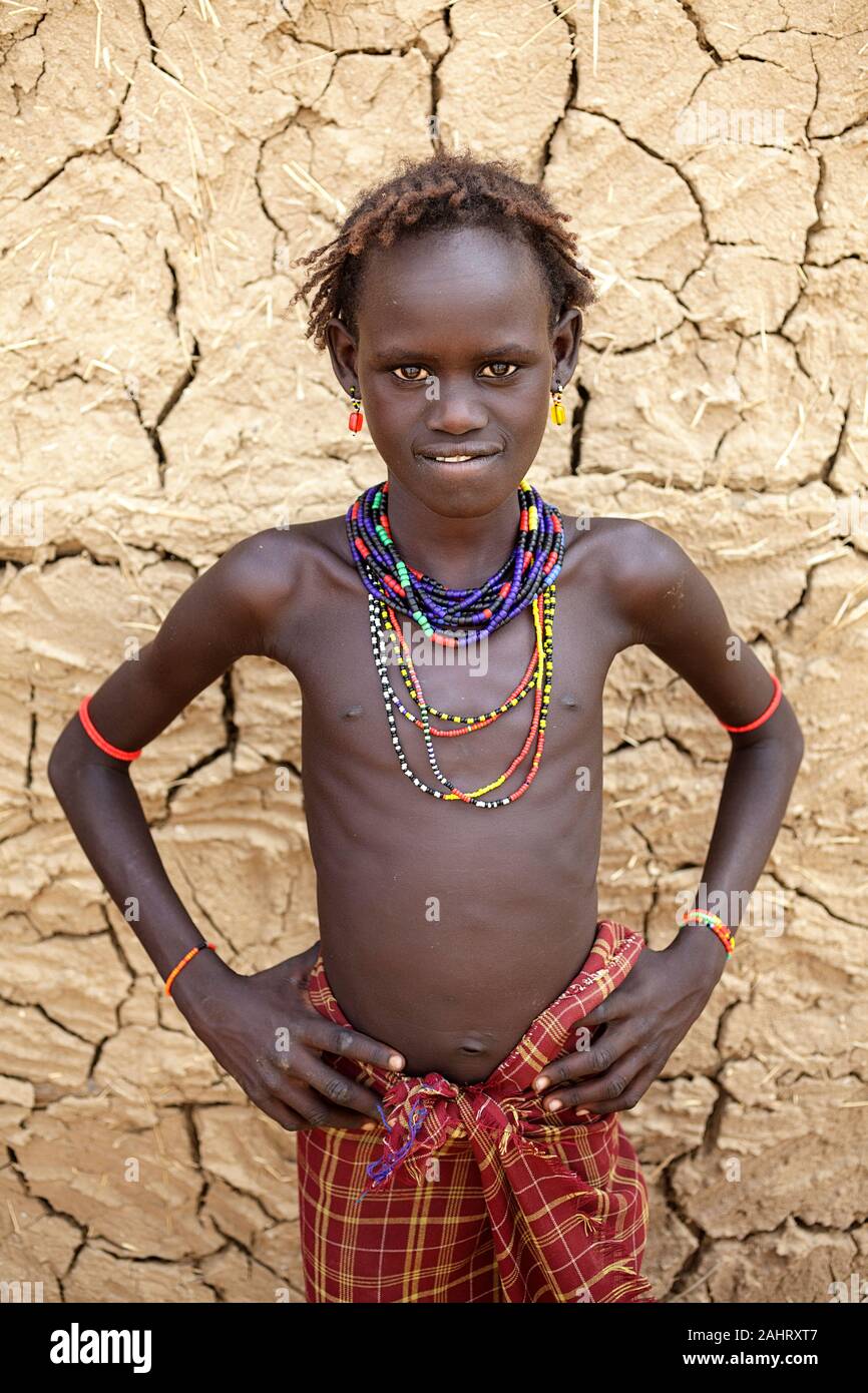 Portrait of a girl from Dassanech tribe in front of a cracked walls of a traditional house, Omo valley, Ethiopia Stock Photo