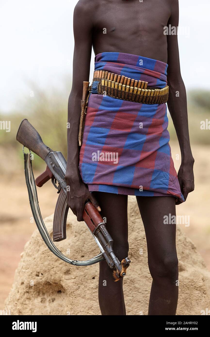 Young man of Dassanech tribe standing holding a gun in his hands, Omo valley, Ethiopia Stock Photo