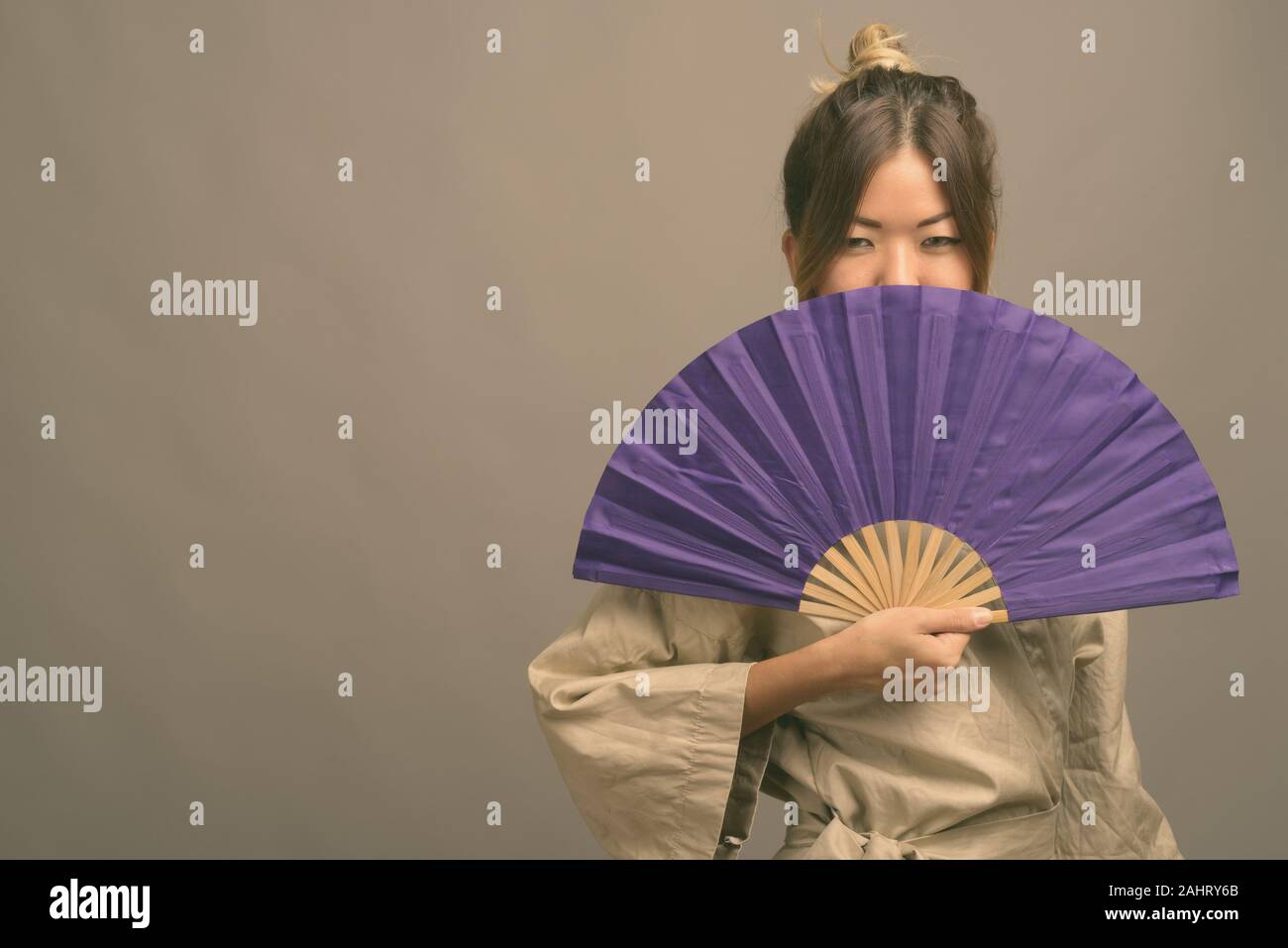 Studio shot of young beautiful Kazakh woman wearing traditional clothes against gray background Stock Photo