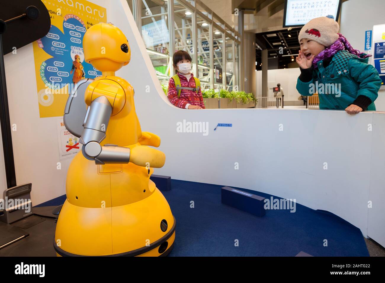 A child attempt to talk with a Wakamaru communications robot at the Mitsubishi Minatomirai