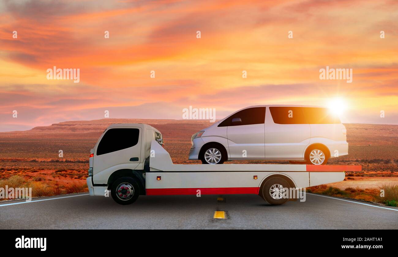 Tow truck delivers the damaged vehicle, Sun light flare. Stock Photo