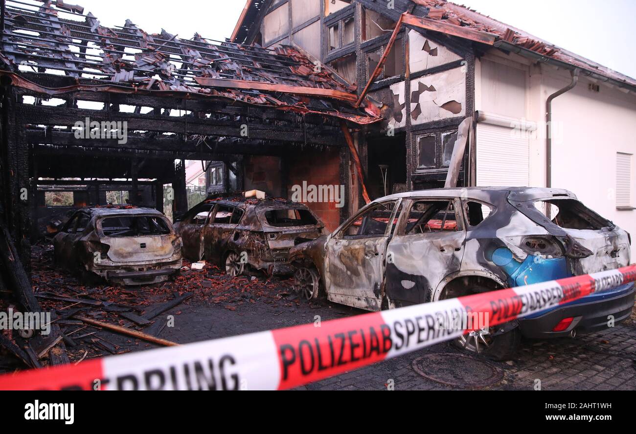 Baden-Wuerttemberg, Biberach-Rißegg, Germany. 1st Jan, 2020.  Burned-out cars stand in a carport between two semi-detached houses, which have also been damaged by fire and are now uninhabitable. On New Year's Day, residents had disposed of burnt fireworks batteries in a plastic trash can. (zu dpa Used fireworks probably start fire in Biberach) Photo: Thomas Warnack/dpa Credit: dpa picture alliance/Alamy Live News Stock Photo