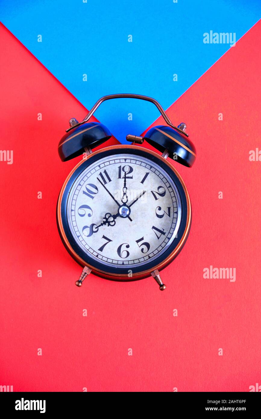 Old retro alarm clock on red and blue background. Stock Photo