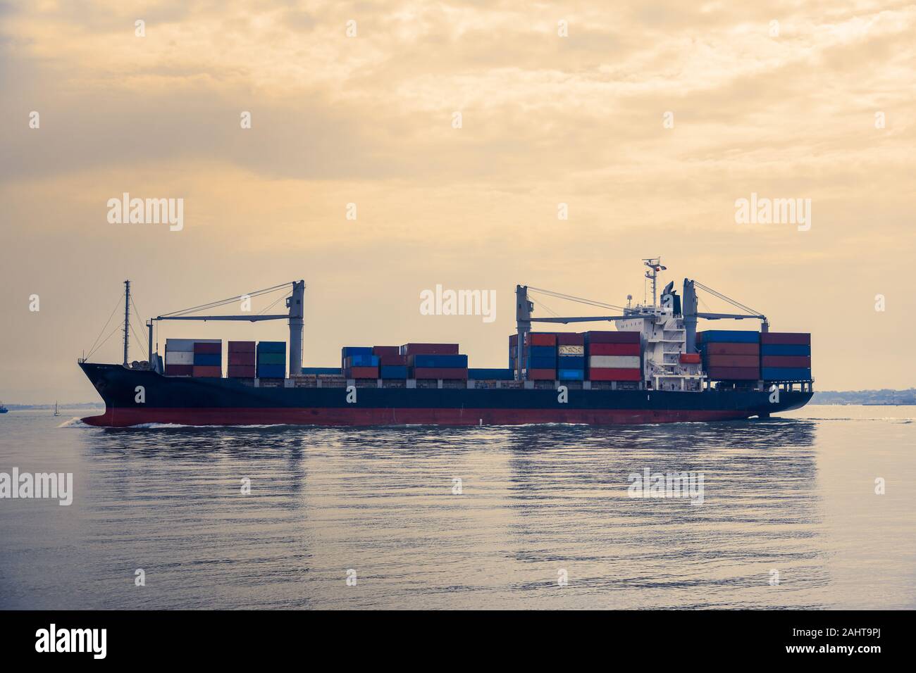 Cargo ships transporting containers in the evening light. Concept of transport and commerce by sea. Lisbon, Portugal. Europe. Stock Photo