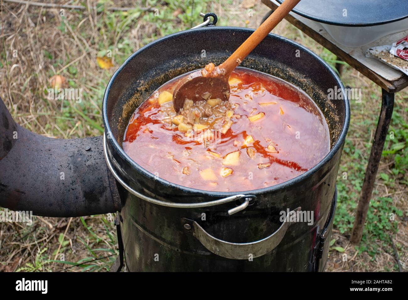 Cooking delicious kettle goulash with meet, pepper, tomatoes, onion in a large cauldron outdoors Stock Photo