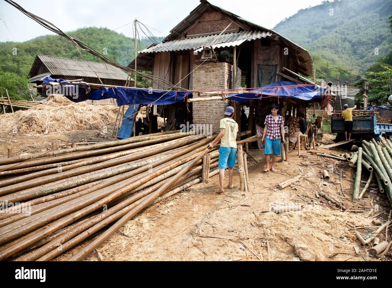 Bamboo chopstick factory at mai Chau.  Men drag bamboo trunks to the sawing machine where a man with a circular saw cuts the trunk to length Stock Photo