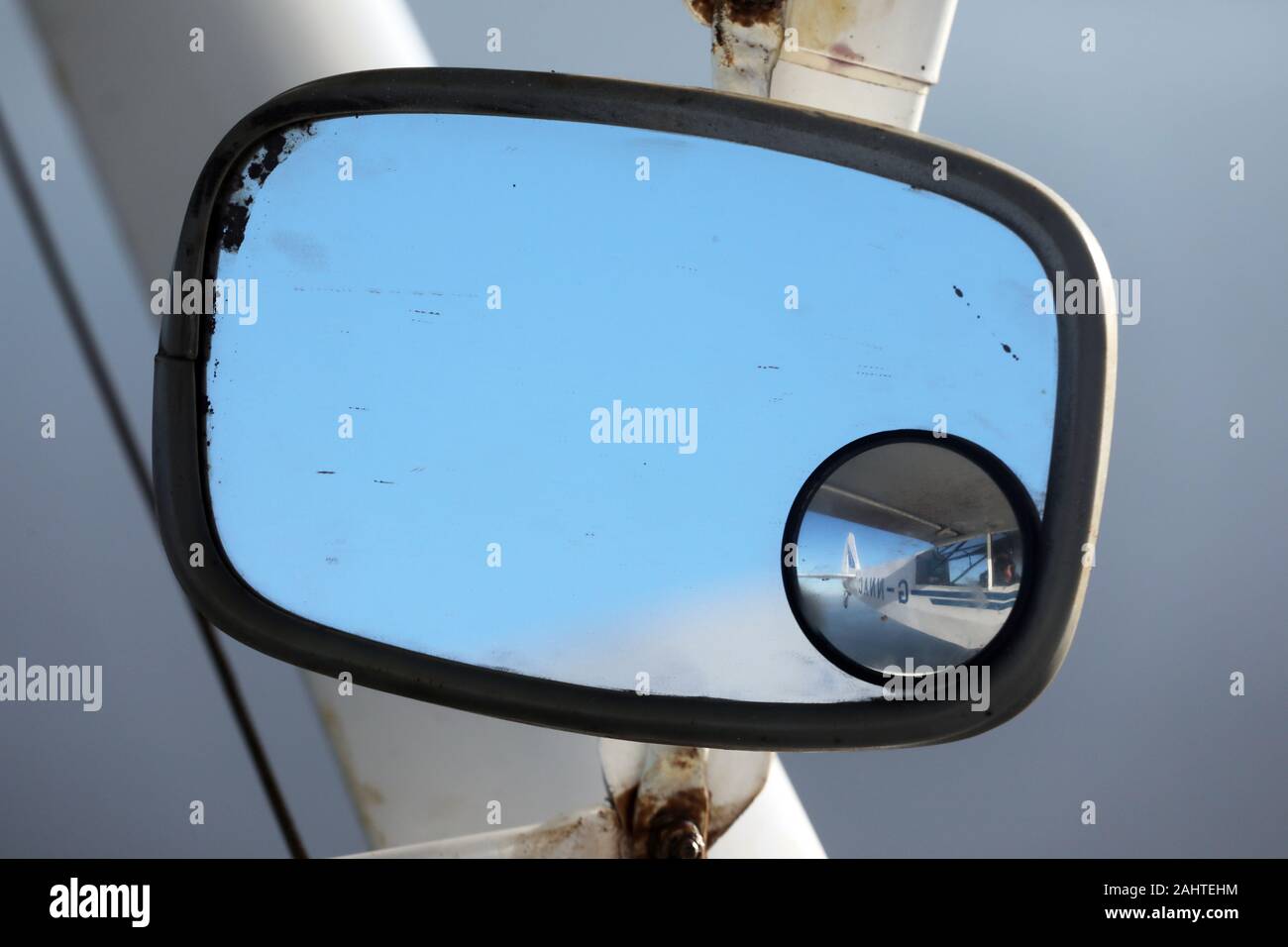 a view in a mirror attached to the wing strut of a Piper PA18 Supercub light aircraft Stock Photo