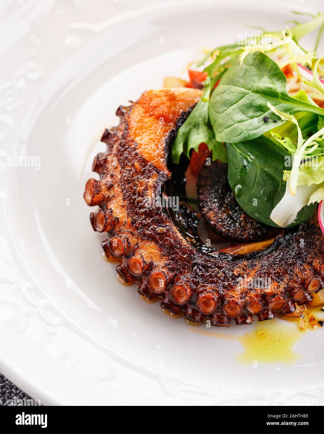 Octopus tentacle fried in a pan with new potatoes and calamata olives