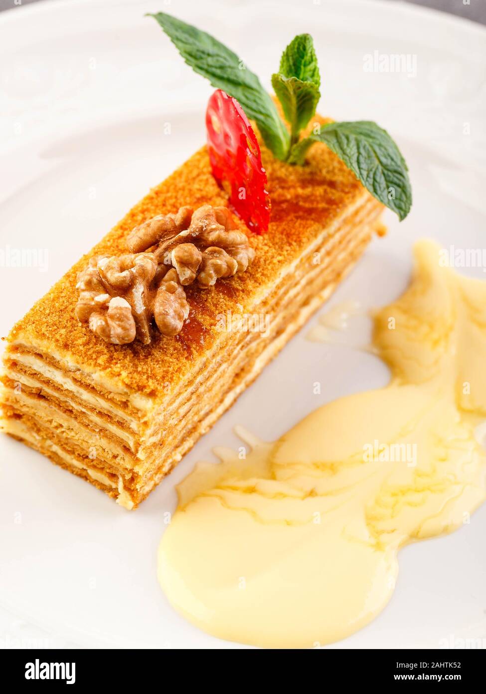 Traditional honey cake decorated with strawberries and mint in a restaurant serving. Russian Honey Cake Medovik Stock Photo