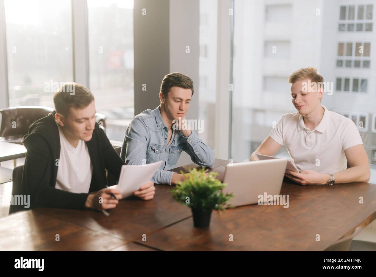 Three young startup men are working on business project in modern ...