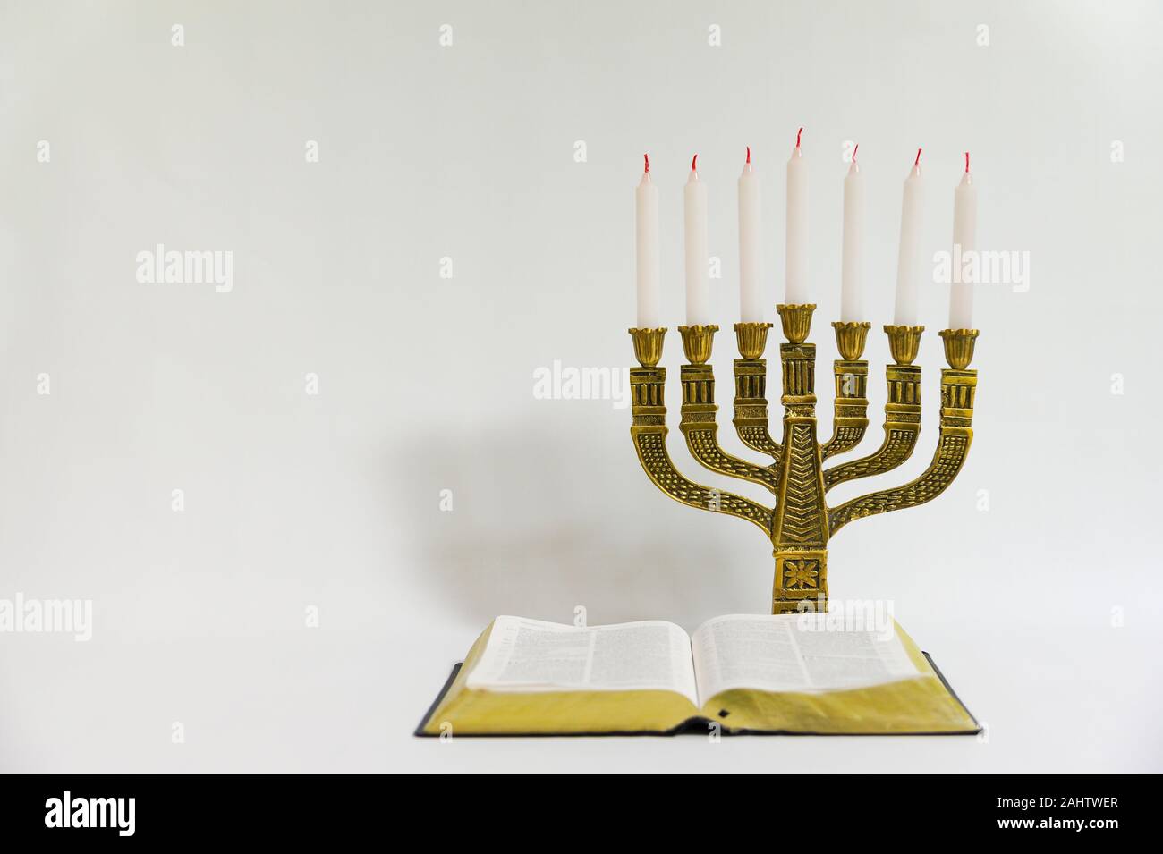 Menorah and open bible with 7 unlit candles isolated on white background. Copy space. Horizontal