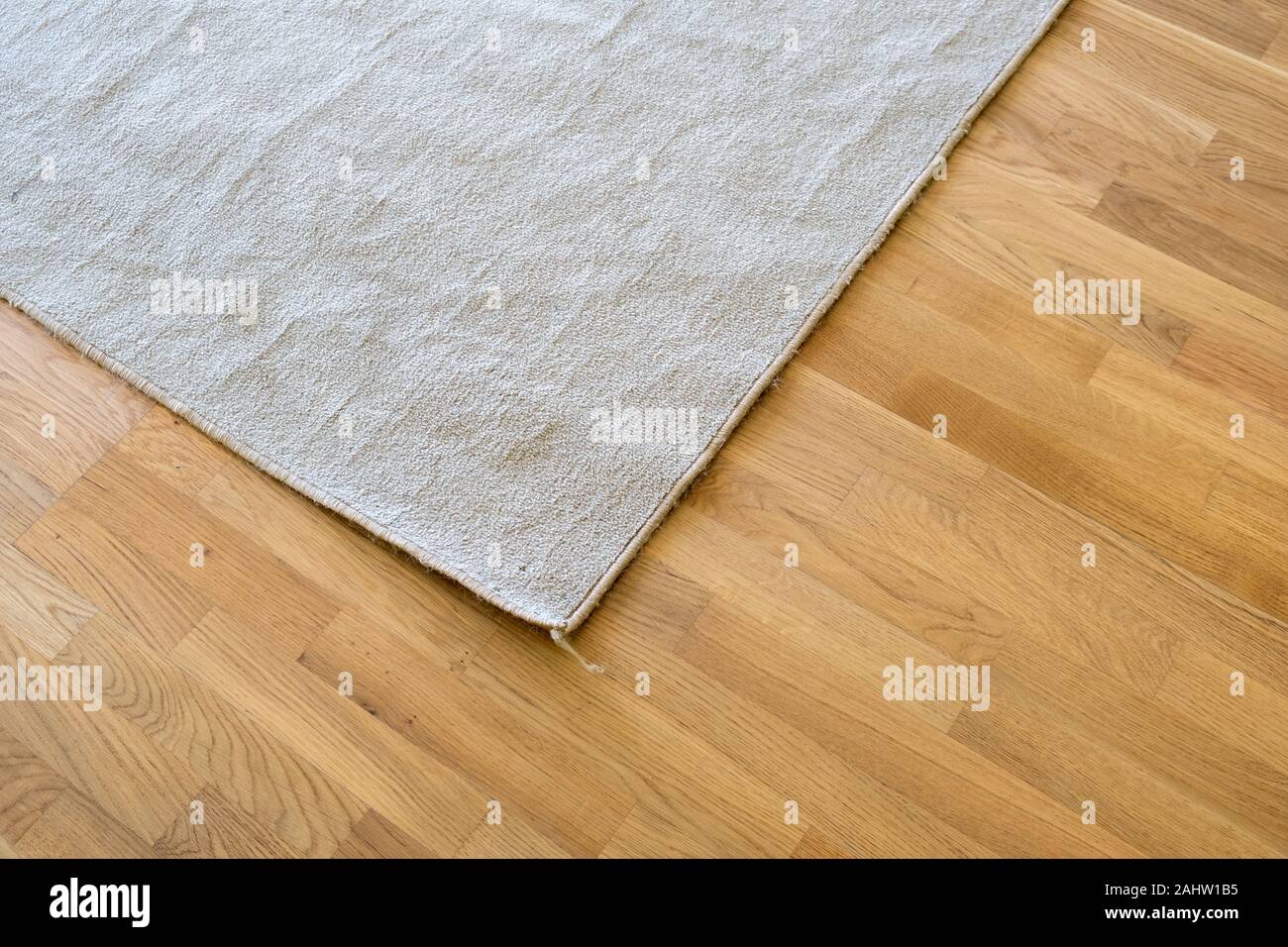 Close Up Of Crumpled Carpet Laying On Parquet Wooden Floor Stock