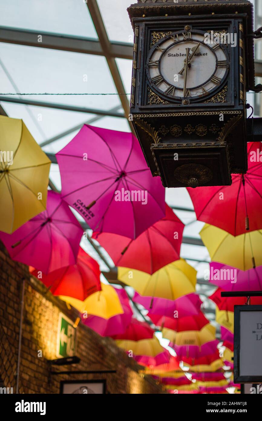 Colorful umbrellas and an old clock hanging in the famous Camden