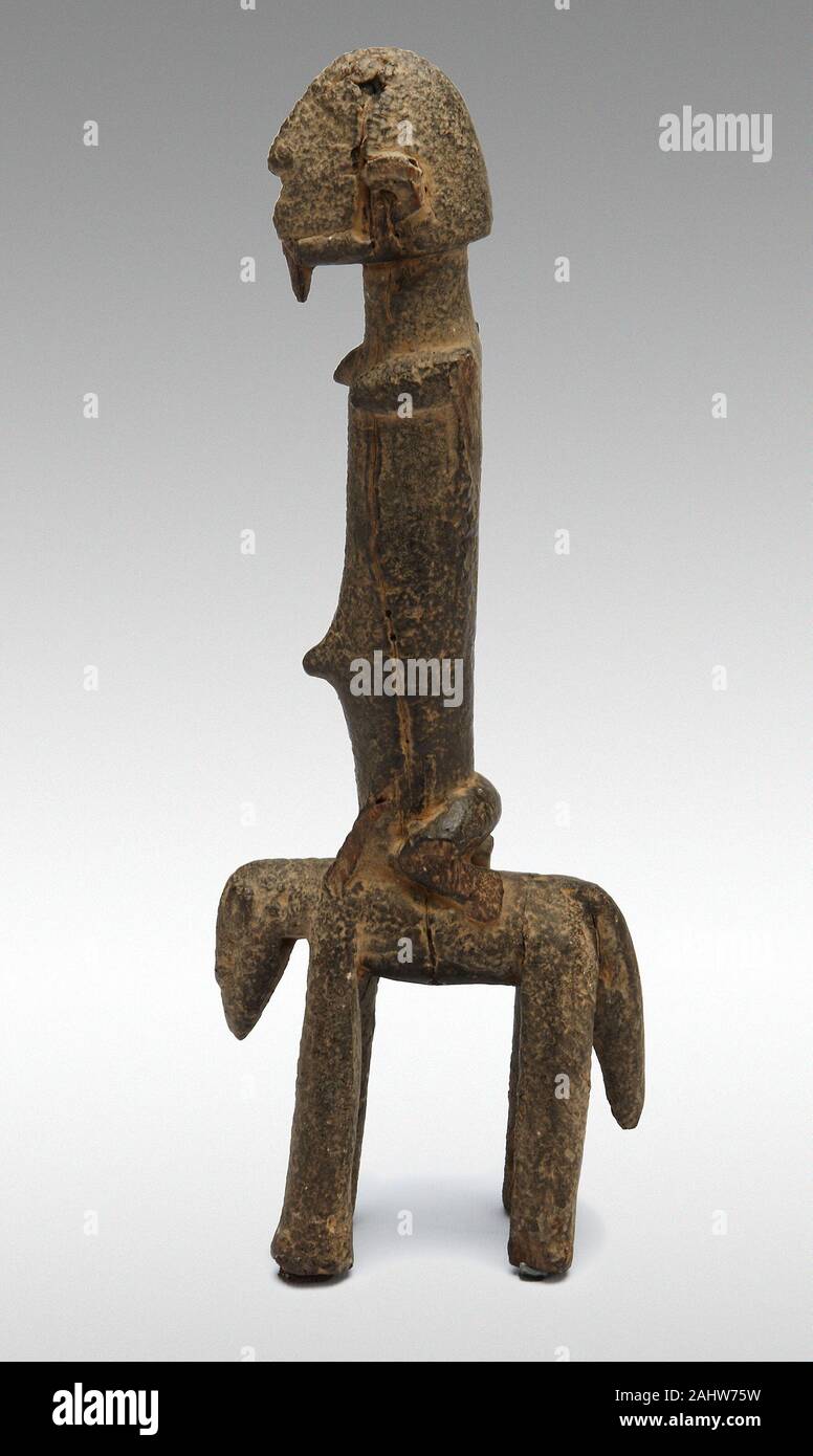 Dogon. Equestrian Figure. 1500–1900. Mali. Wood and sacrificial material In the 15th century, Dogon people fleeing hostilities in their homeland—caused by slave raiders’ incursions and the expansion of Islam—migrated to the rocky Bandiagara Escarpment in present-day Mali, where they encountered the Tellem people. While the Dogon eventually expelled the Tellem from the region, the two peoples appear to have influenced each other’s sculptural styles. This horse-and-rider features the pared-down style and encrusted surface associated with sculptures made by the Tellem. Stock Photo