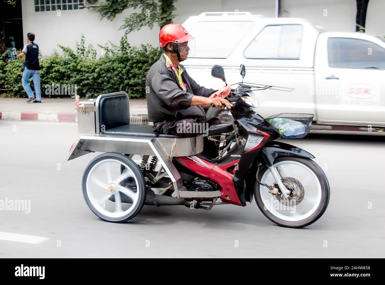 SAMUT PRAKAN, THAILAND, OCT 10 2019, A man rides a modified motorbike in the city streets. Handicapped biker on tricycle. Stock Photo