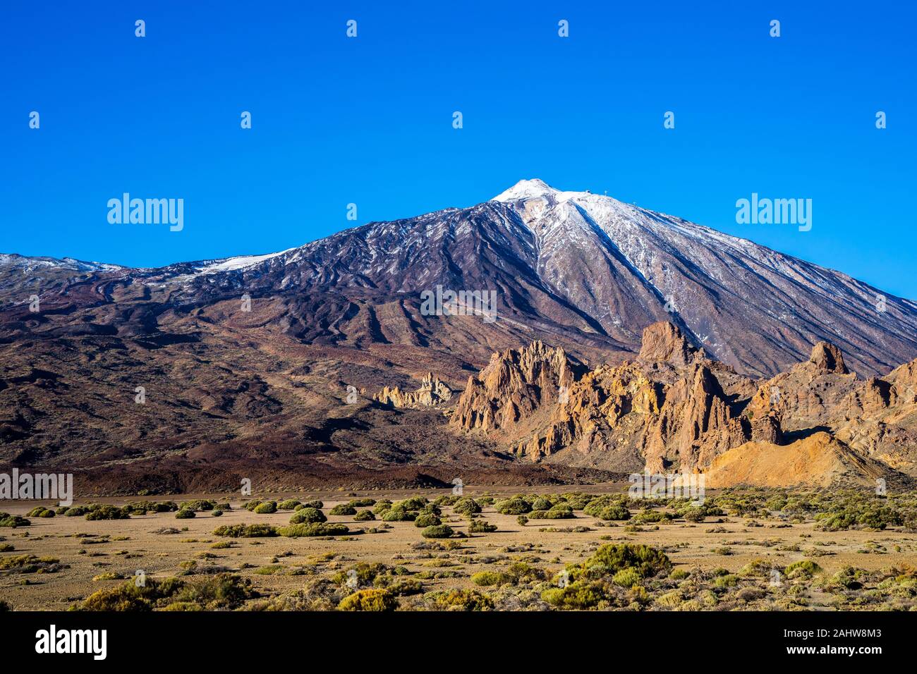 Spain, Tenerife, Rocky caldera desert surrounding snow covered summit of mountain teide volcano in winter with blue sky in the evening Stock Photo