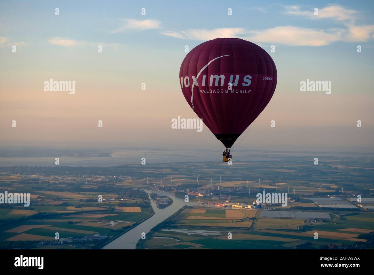 The Ghent-Terneuzen canal passes Sluiskil, going to the locks. A hot air balloon with publicity of telecommunications group Proximus flies high. Stock Photo