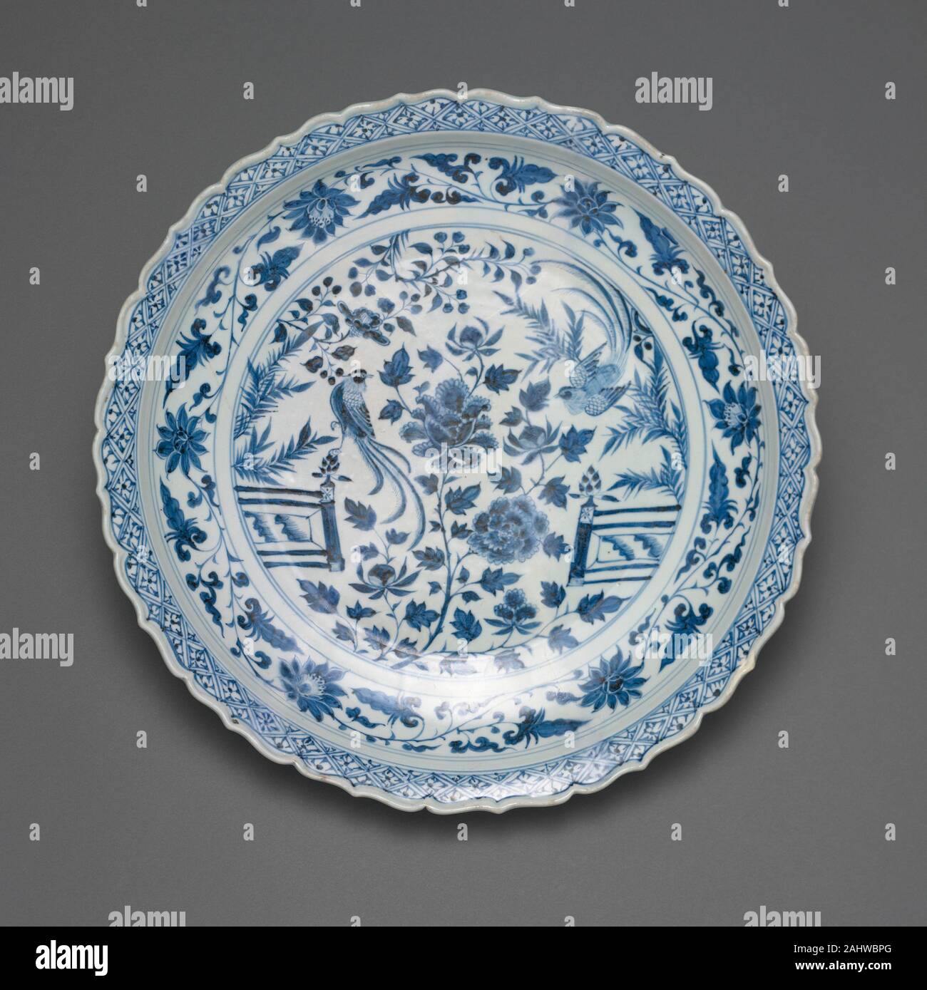 Shallow Dish with Long-Tailed Birds in a Garden of Stylized Peonies and Fronds, Encircled by a Scrolling Wreath of Camellia and Lotus Blossoms. 1300–1350. China. Porcelain painted in underglaze blue Stock Photo