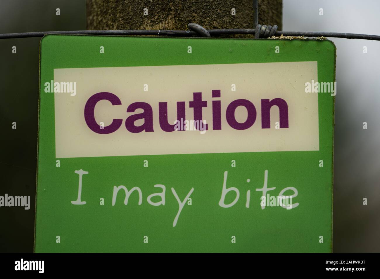 Green sign 'Caution I may bite' on an animal enclosure at a zoo Stock Photo