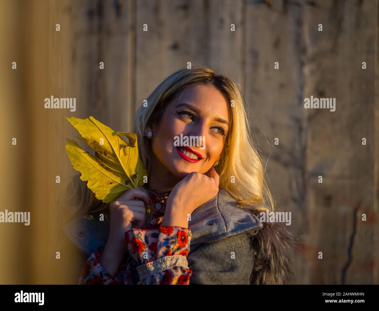 Portrait head and shoulders with Autumn leaf in hand looking away aside in distance setting sun sunset nature natural environment memory Stock Photo