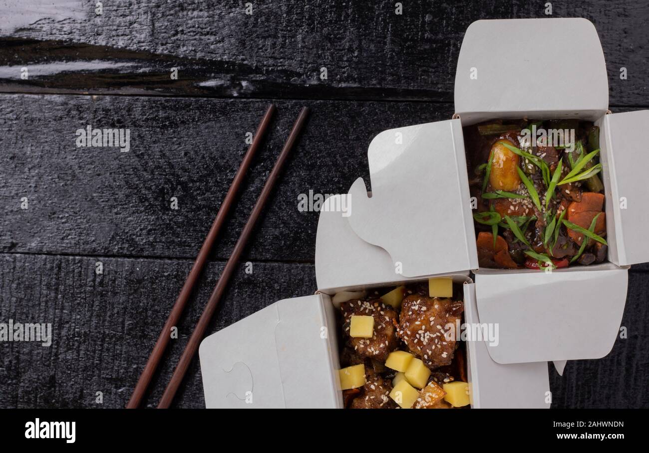 Delicious wok noodles box container with udon and chicken on wooden