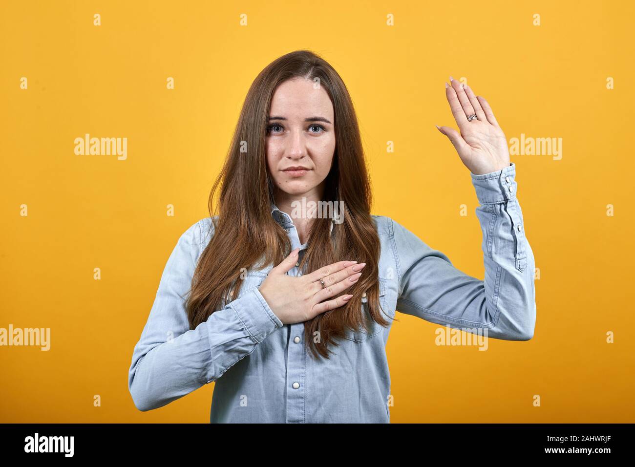 Attractive woman giving promise, keeping hand on chest and shoing palm at camera Stock Photo