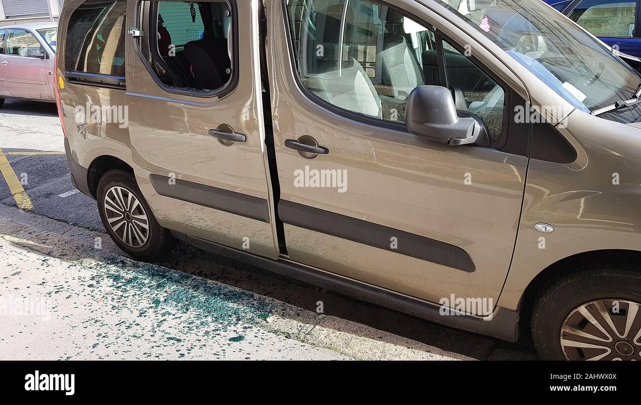 Broken rear side window of a car by thief with broken glass on the