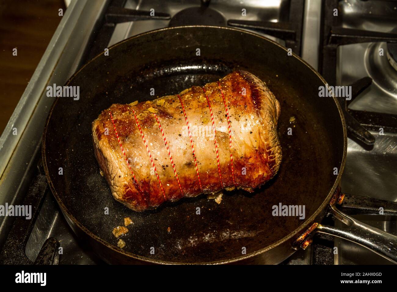 On a gas hob browning a rolled beef brisket joint Stock Photo Alamy