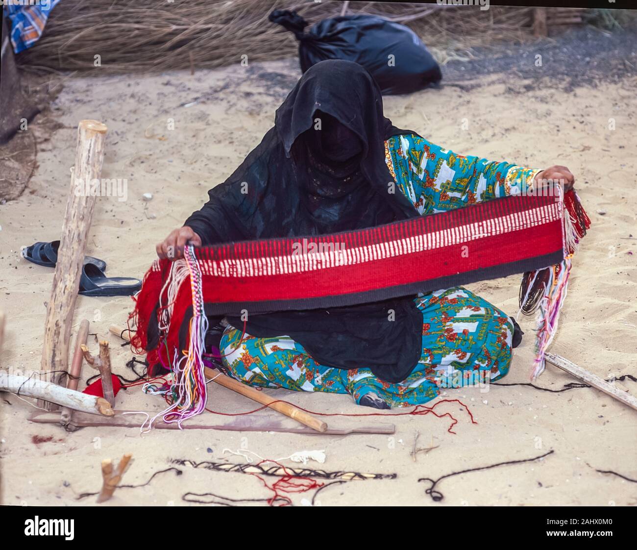 Dubai Arab folklore and history with an Emirati woman demonstrating weaving skills at the Shindagha Heritage Village located at the mouth of the Dubai Creek during the Dubai Trade Show and Festival in the United Arab Emirates Stock Photo