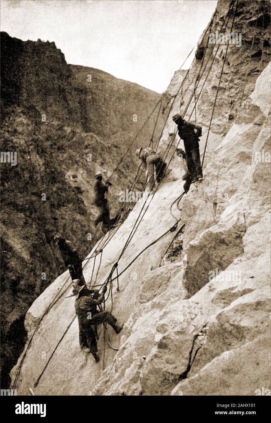 An historic,  1930s photograph showing the building of the Hoover Dam aka Boulder Dam , Black Canyon, Colorado River, on the border between the U.S. states of Nevada and Arizona. This view shows 'high fliers', construction men who worked on the rocks attached to ropes and safety lines. Stock Photo