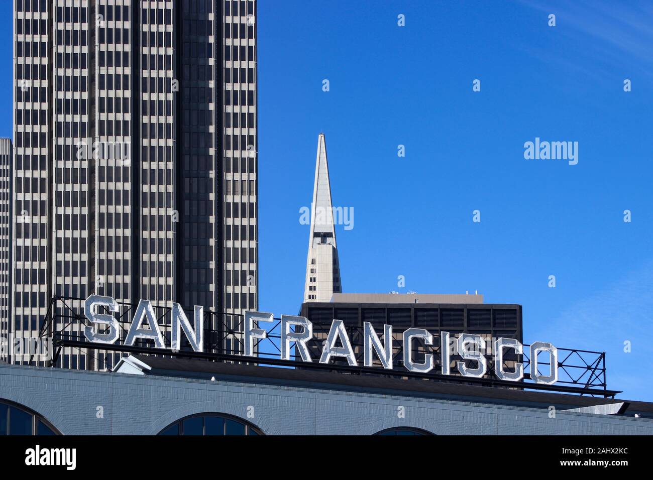 San Francisco neon letters on top of Ferry Building. Embarcadero Center and tip of the Transamerica Pyramid in the background. California, USA. Stock Photo