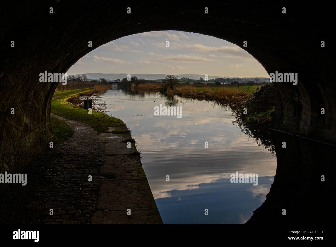 A quintessentially English view of Lancaster canal framed within the arch of a bridge over the canal between Glasson Dock and Conder Green Stock Photo