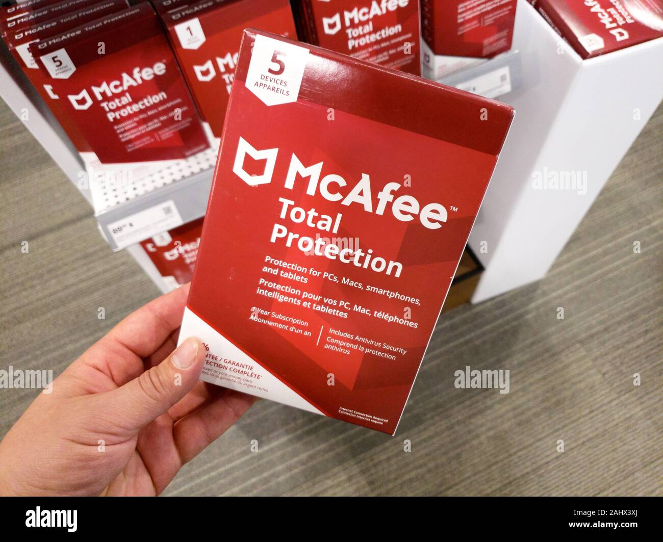 Montreal, Canada - December 26, 2019: A hand holding McAfee Total Protection box with license and program. McAfee is an American global computer secur Stock Photo