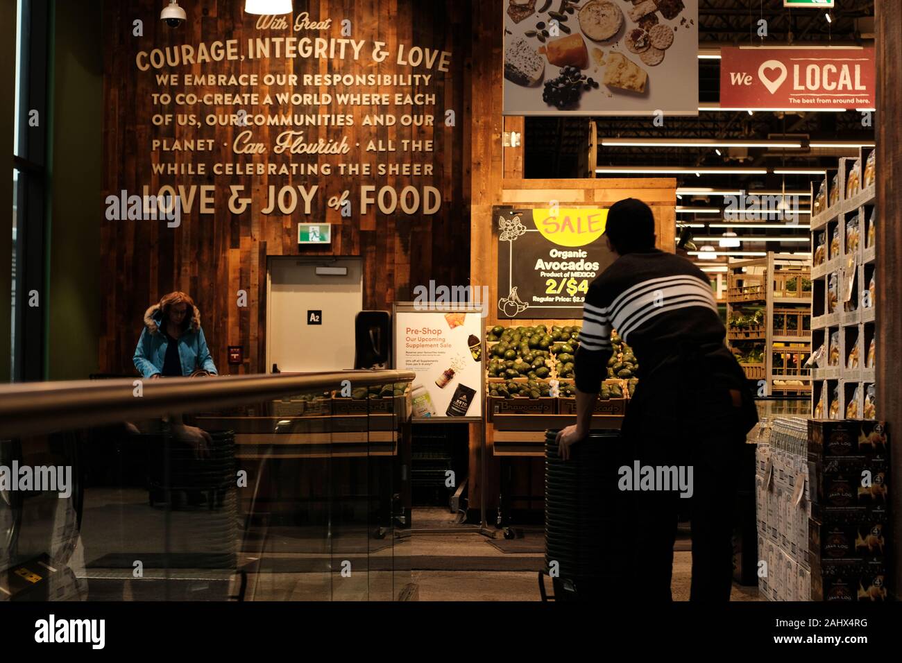 Clerk returning shopping baskets at the entrance to the local Whole
