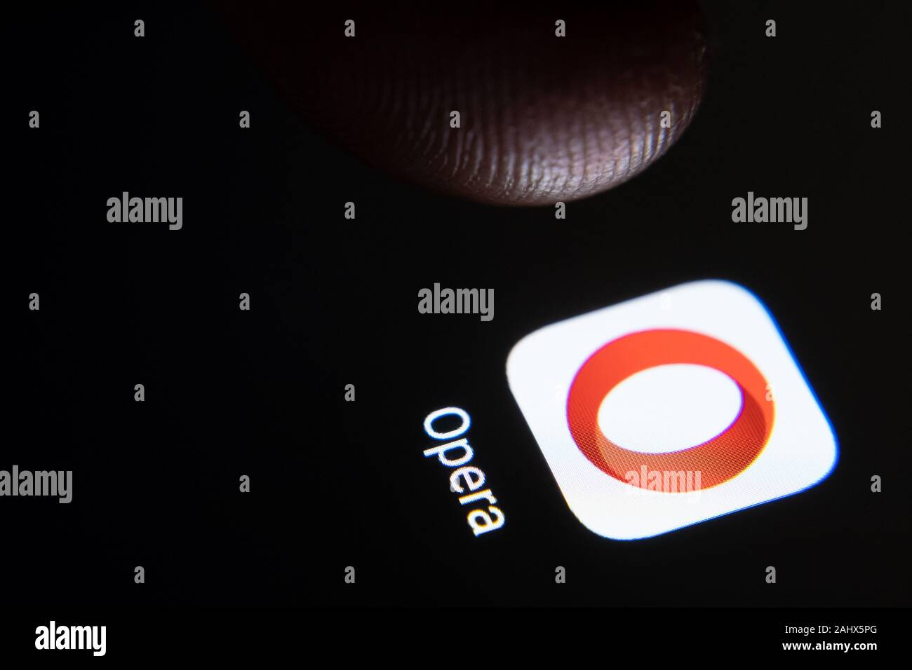 Opera browser app icon on the smartphone screen and finger launching it. Stock Photo