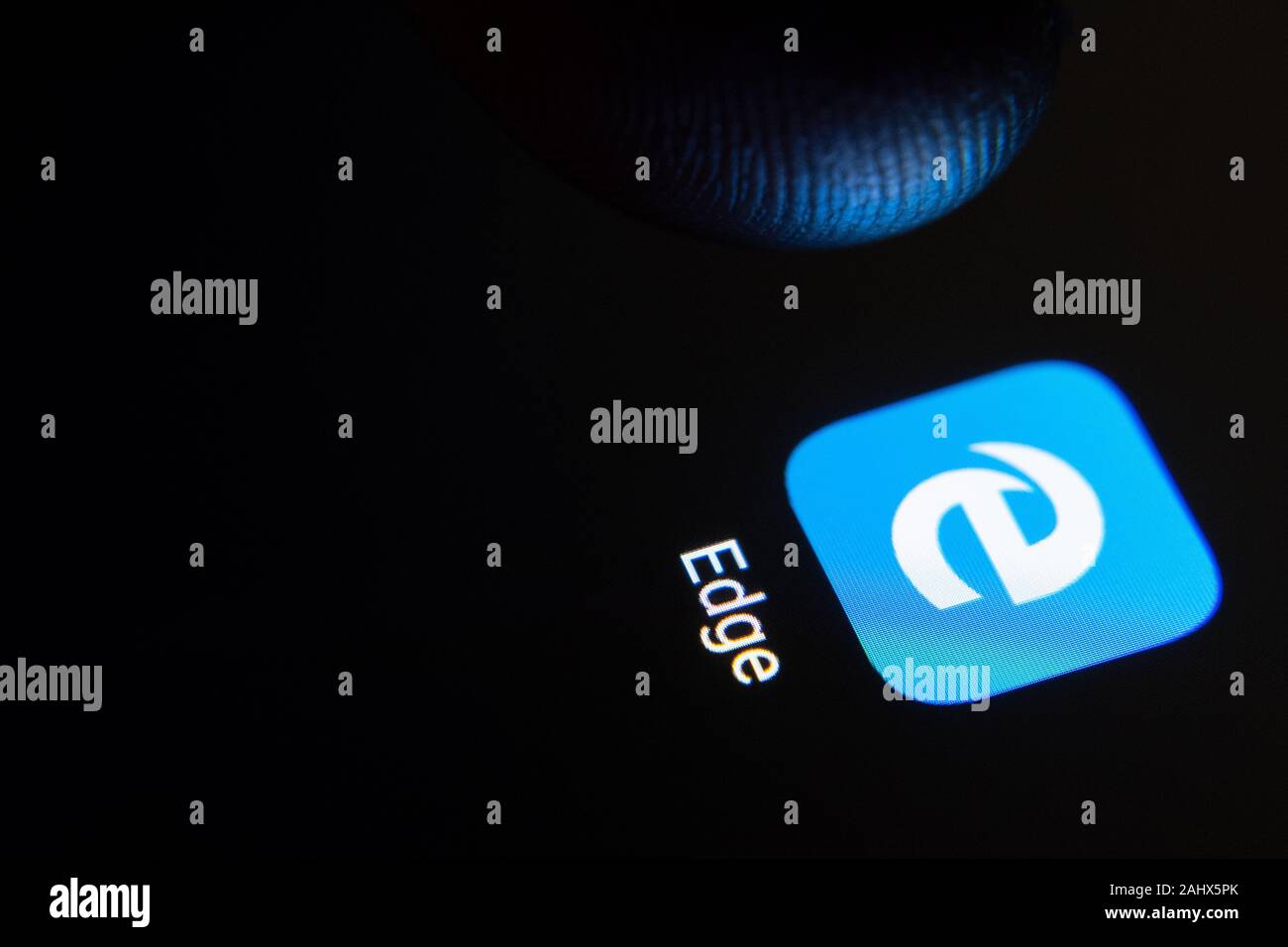Edge browser app icon on the smartphone screen and finger launching it. Stock Photo