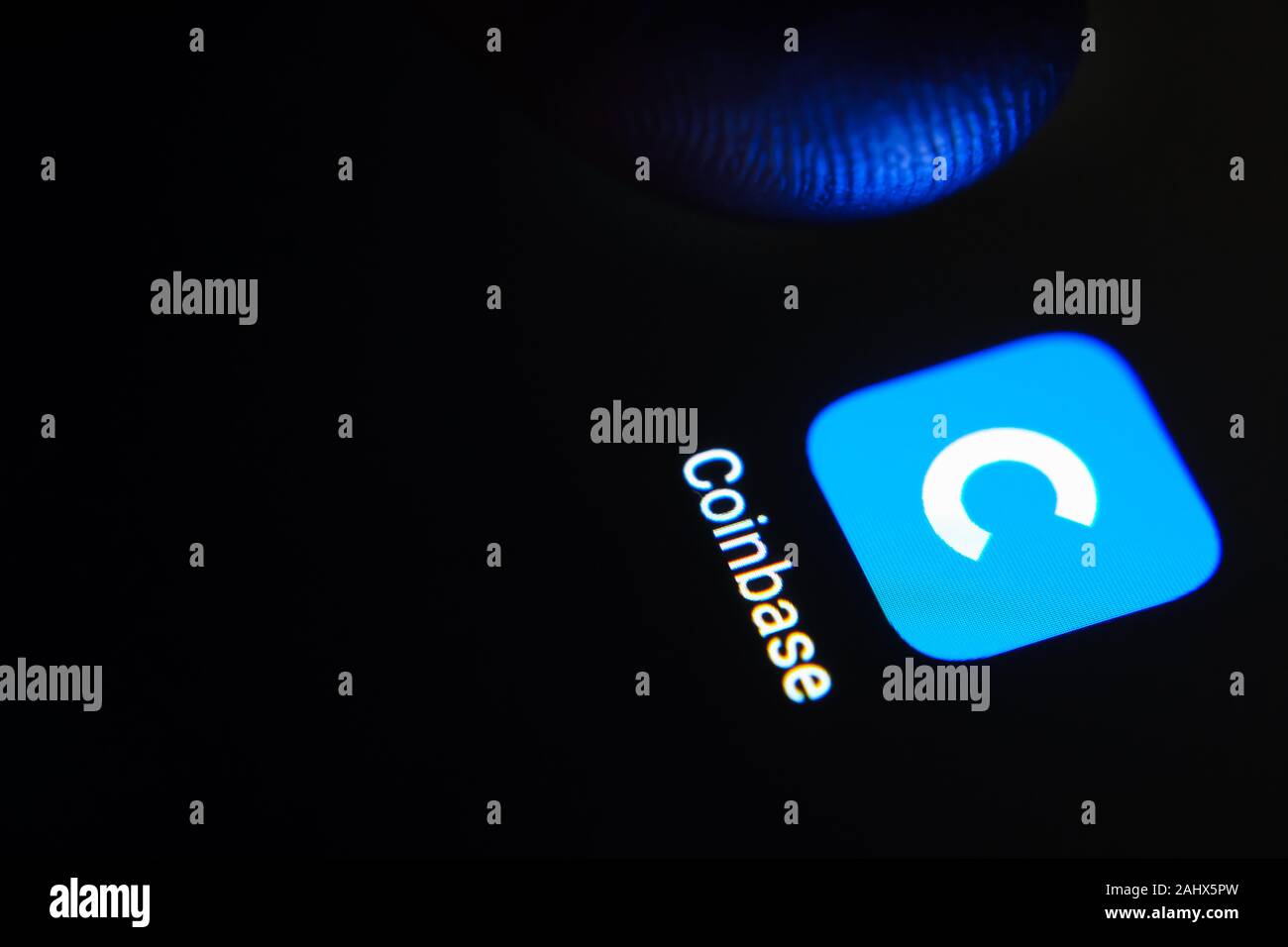 Coinbase app icon on the smartphone screen and user launching it. Coinbase is a digital currency exchange service. Stock Photo