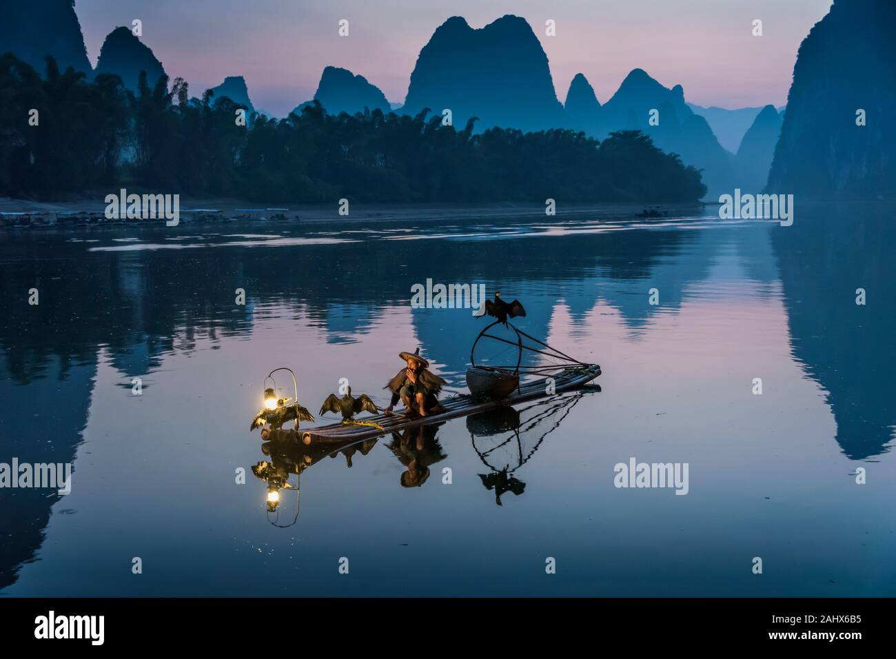 Cormorant fisherman taking early morning smoke break, Li River, Xingping, Guilin, China Stock Photo