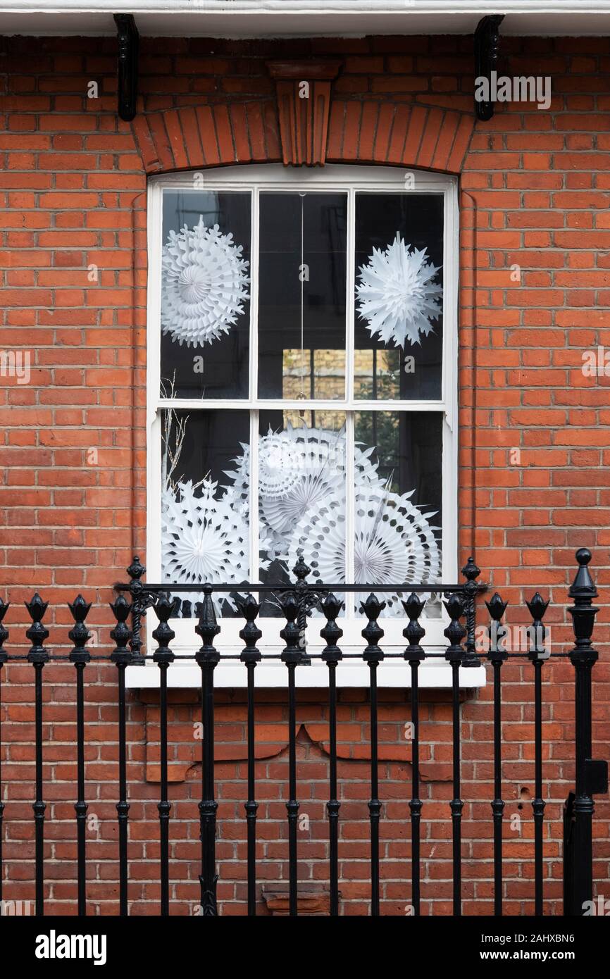 Christmas paper snowflake decorations in a house window. Chelsea, London, England Stock Photo