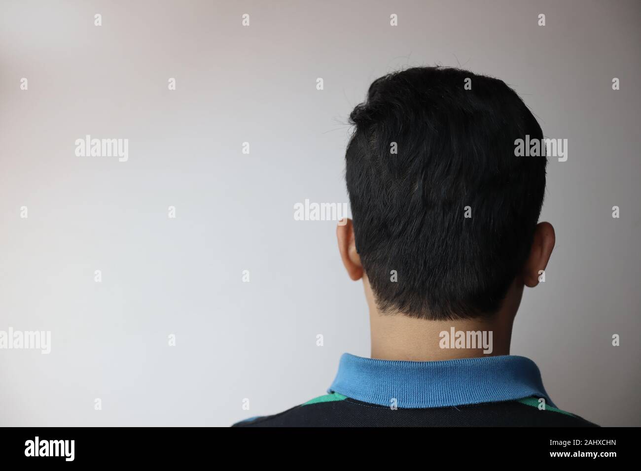 back of the head of a young indian male with copy space for text isolated on grey Stock Photo